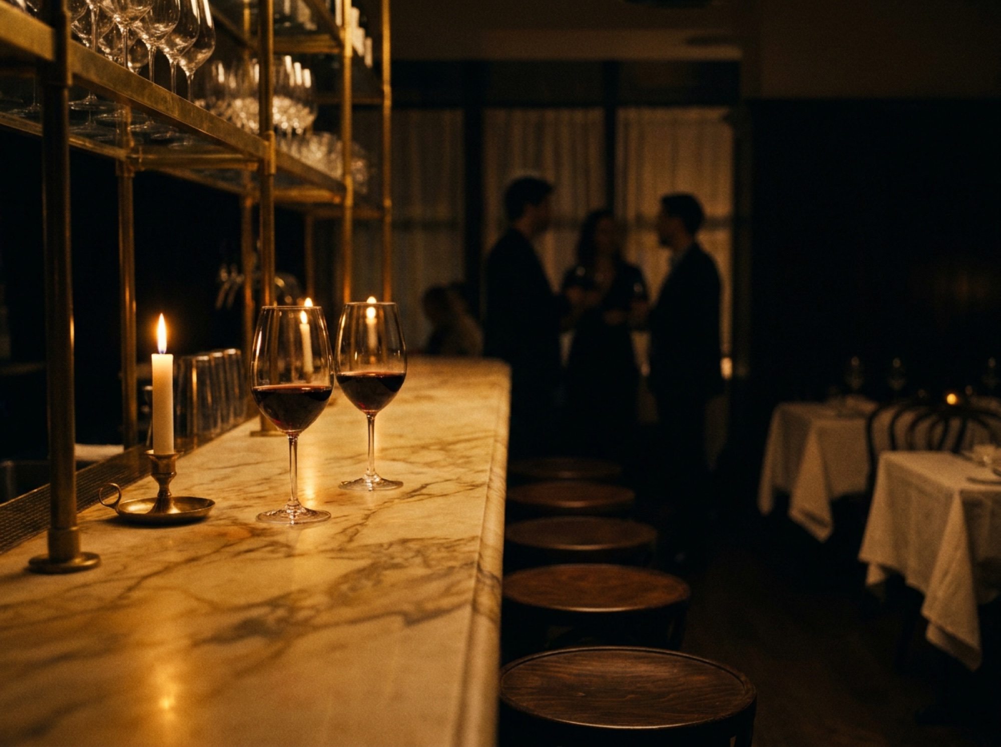 A candlelit marble bar with wine glasses and brass fittings
